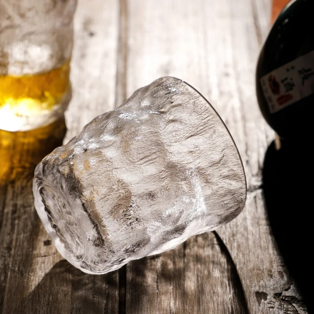 Handcrafted retro-inspired whisky glass with a unique textured surface, placed on its side on a wooden table.