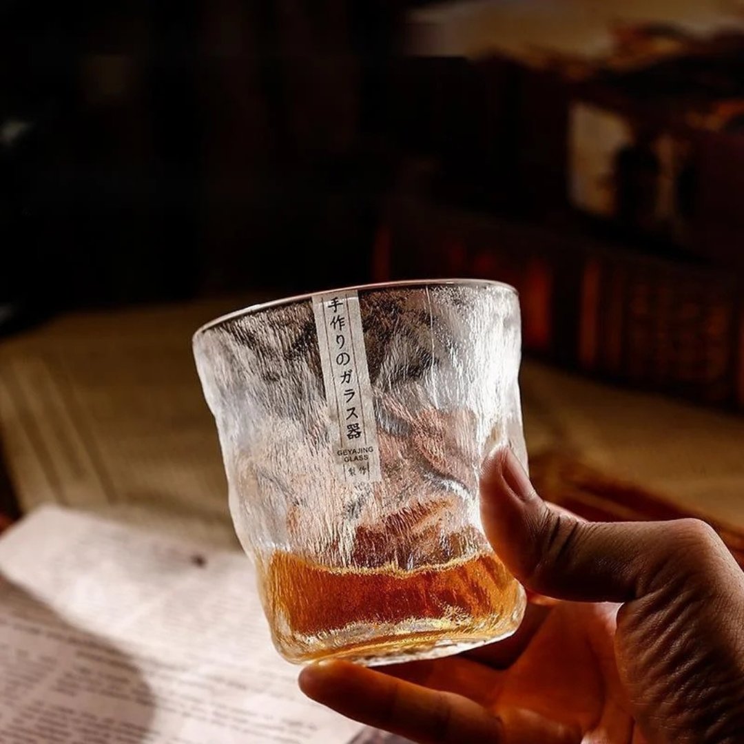 Hand holding our handcrafted retro-inspired whisky glass with a unique textured surface, filled with whisky.