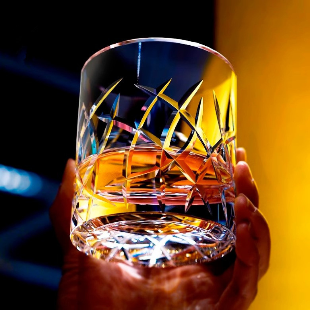 Hand holding our handcrafted crystal whisky glass with intricate Kiriko cut design inspired by ocean waves, featuring a heavy bottom for a luxurious feel.