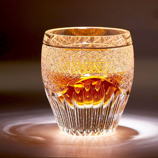 Handcrafted K9 crystal whisky glass with an intricate Edo Kiriko design, filled with whisky, glowing under warm ambient lighting.