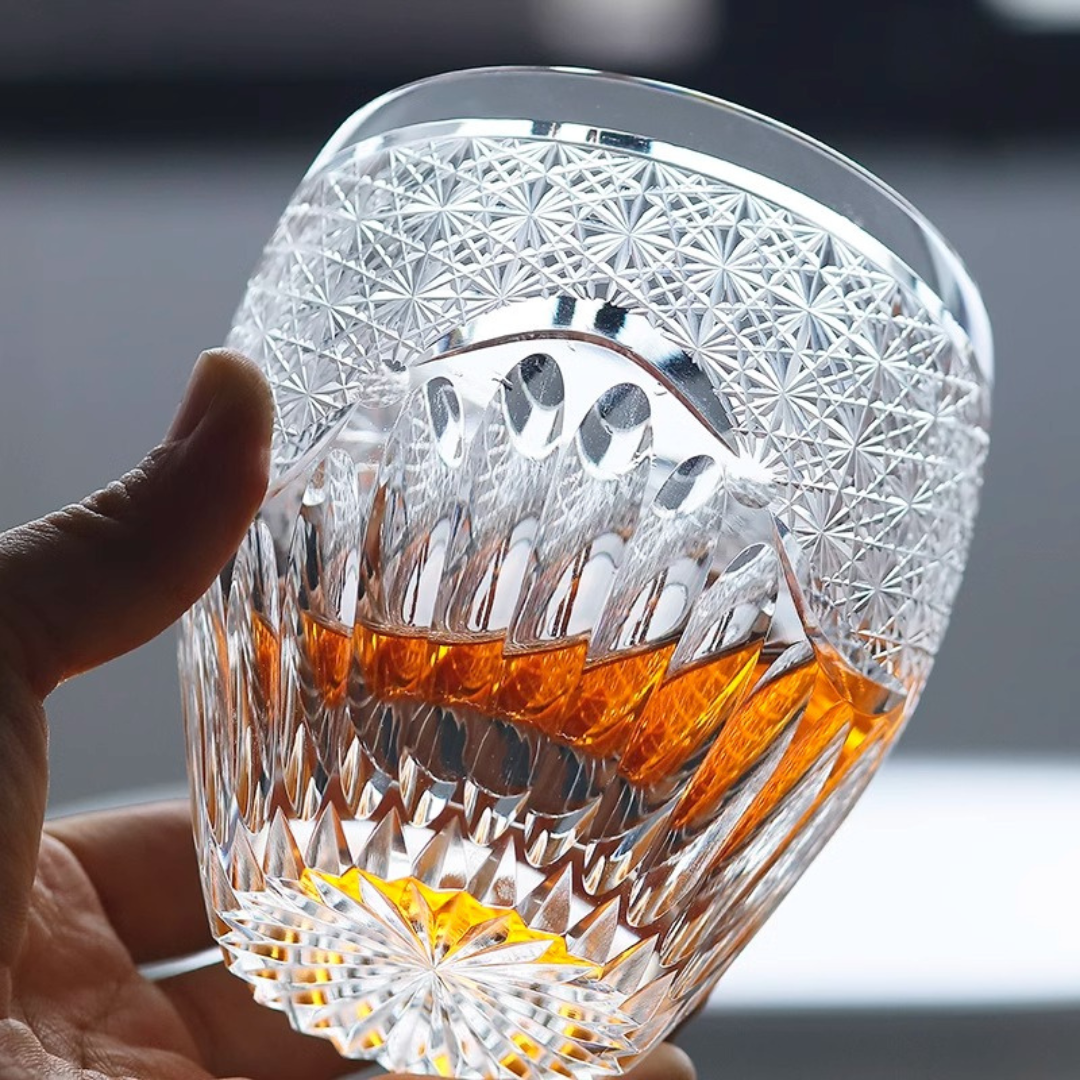 Hand doling our handcrafted K9 crystal whisky glass with an intricate Edo Kiriko design, filled with whisky and showing its intricate details.